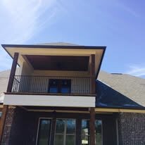 Dark gutters on the roof over a second-floor balcony